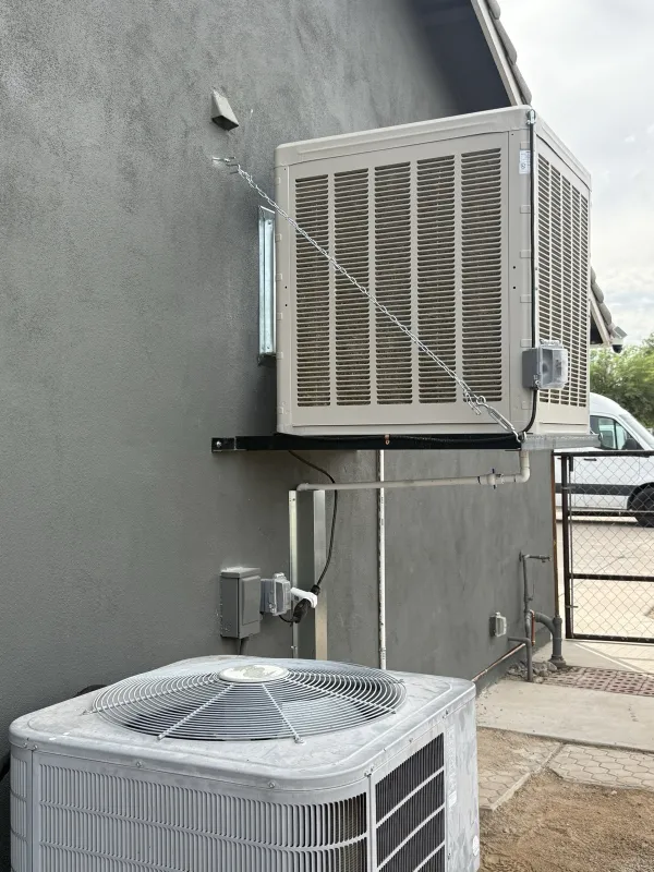 Wall-mounted evaporative cooler installed on a cut-in platform with bracing